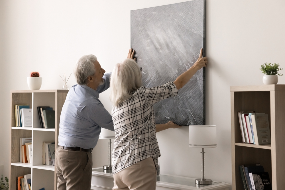 Staří manželé visící na nástěnném výtvarném obrázku v útulném moderním obývacím pokoji, zdobení domácího prostoru, změna designu s novým krásným stylovým uměleckým dílem.